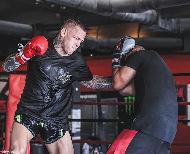 Coach holding pads for a fighter working combinations in the ring