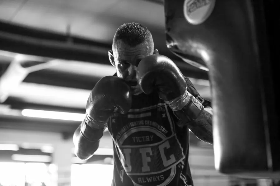 Boxer working the heavy bag under the gym lights